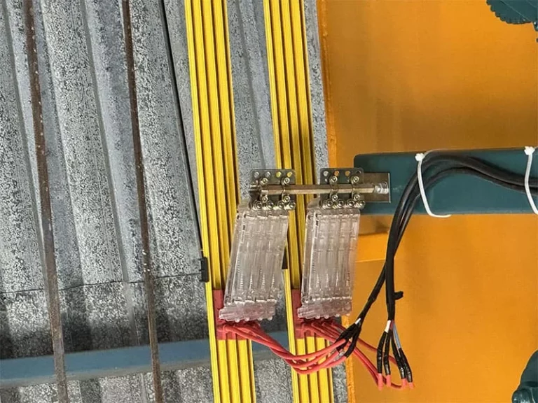 Conexões elétricas com cabos vermelhos e pretos em barra metálica com isolamento amarelo, ilustrando um artigo da Yathon sobre barramento elétrico.