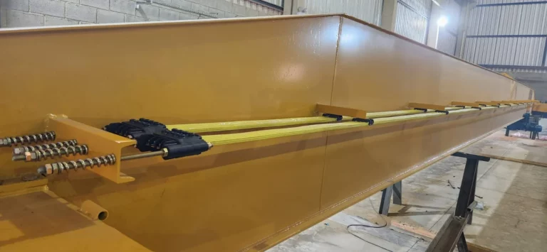 Estrutura metálica amarela com cabos de aço tensionados em ambiente industrial, representando um artigo da Yathon do Brasil sobre ponte rolante.